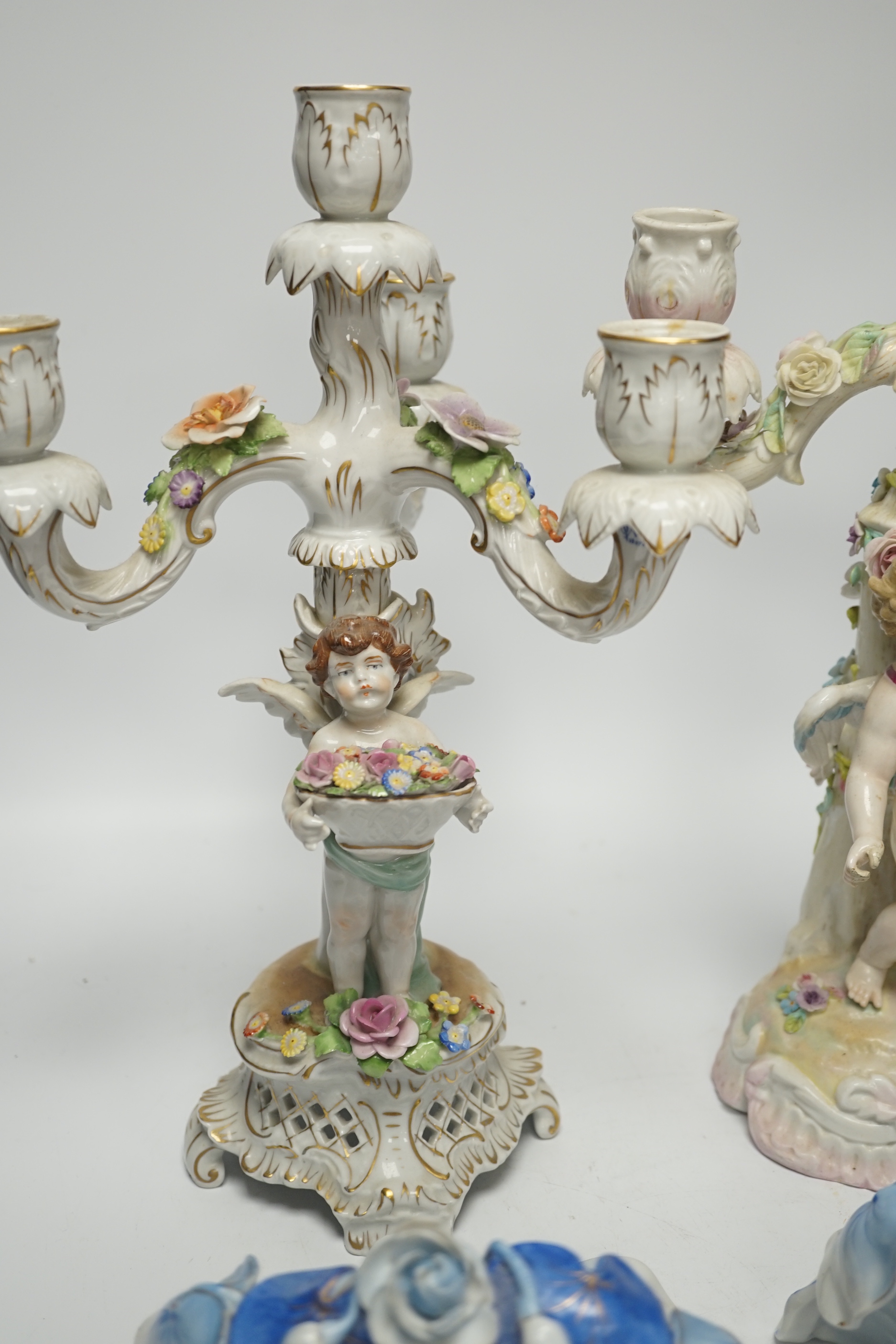 Two continental putti floral encrusted candelabra and two wall pockets, tallest 36cm high